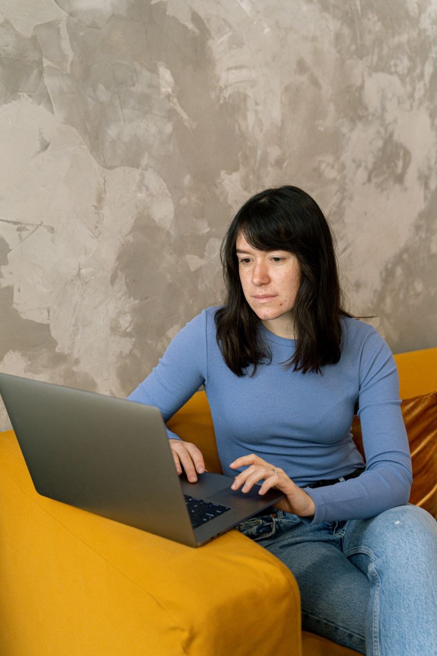 A woman working on her laptop on a sofa at home